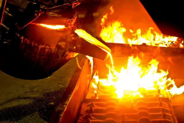 besi cair dituang dari ladel ke cetakan dalam proses pengecoran besi cor nodular