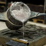 molten aluminum poured from a ladle into a mold in a foundry