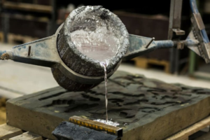 molten aluminum poured from a ladle into a mold in a foundry