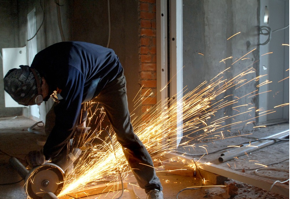 Operator fettling a metal casting with a grinder in a foundry