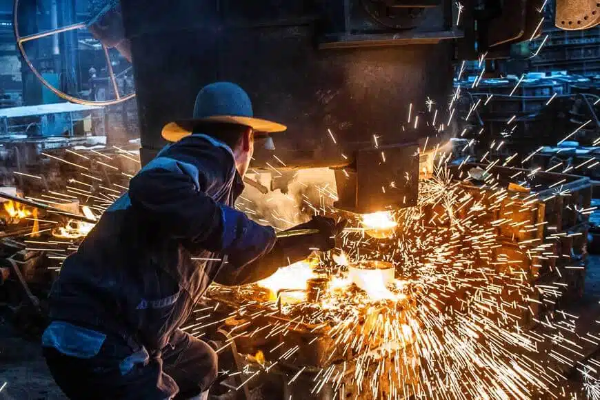 Workers pouring molten metal into a sand mold at a foundry in Ceper, Klaten, Indonesia