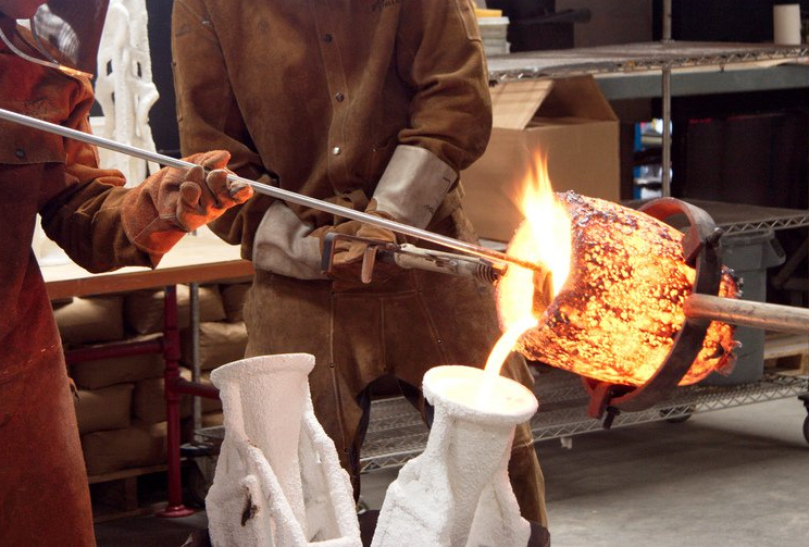 Brass casting process, molten metal poured from a crucible into a sand mold