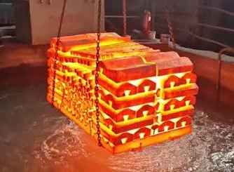 Red-hot steel parts being lowered into a quench tank during quenching and tempering